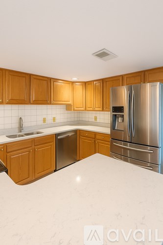 A kitchen with wooden cabinets and a stainless steel refrigerator.