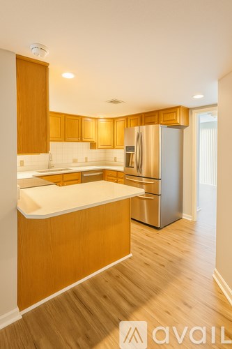 A kitchen with wooden cabinets and a stainless steel refrigerator.