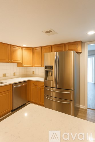 A kitchen with wooden cabinets and a stainless steel refrigerator.