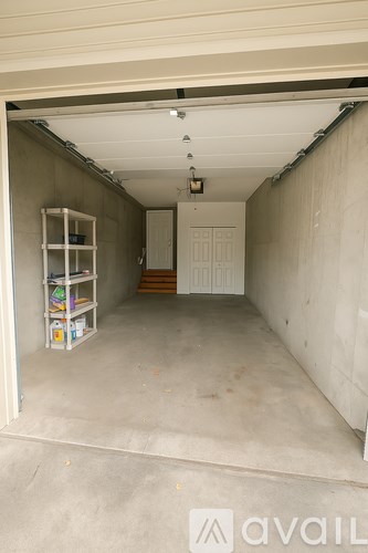 A garage with a white door and shelves on the left side.