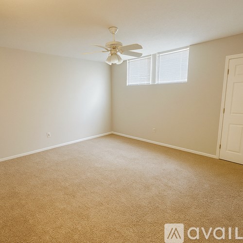 A room with a ceiling fan and carpeted floor.