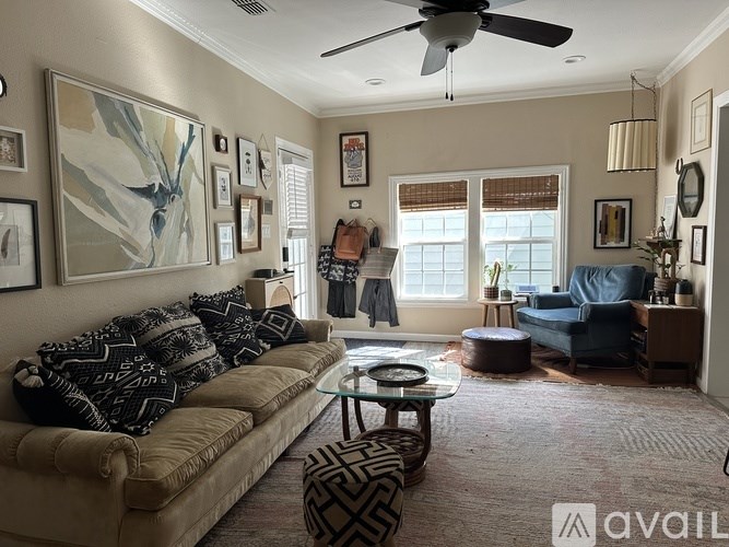 A living room with a beige couch, a coffee table, and a ceiling fan.