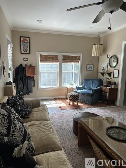A living room with a couch, a chair, and a fan.