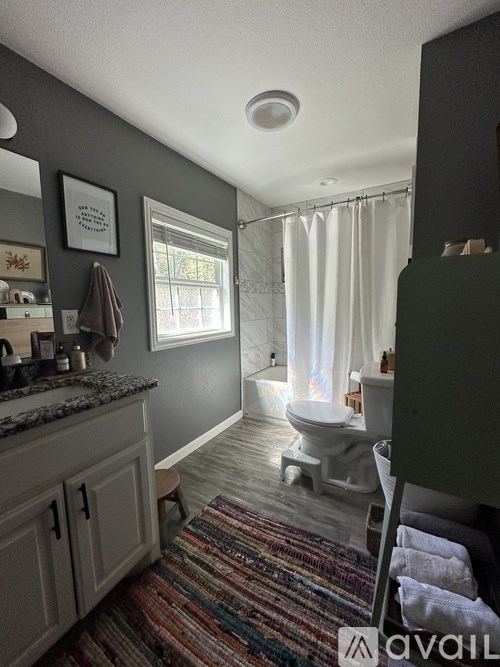 A bathroom with a toilet, sink, and a window.