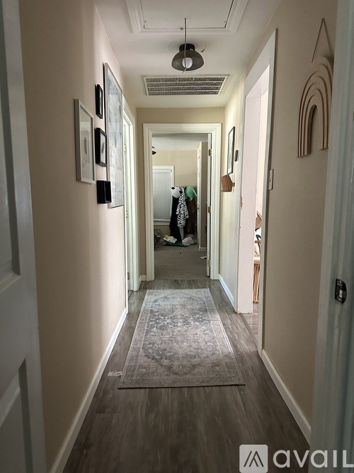 A hallway with a rug on the floor and pictures on the wall.