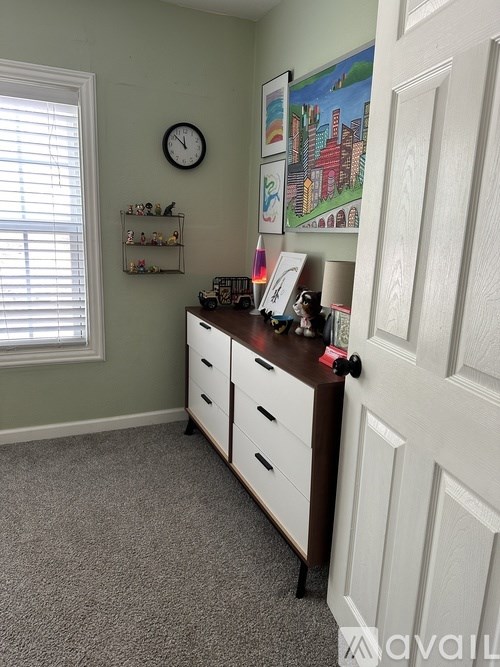 A room with a clock on the wall and a cabinet with drawers.