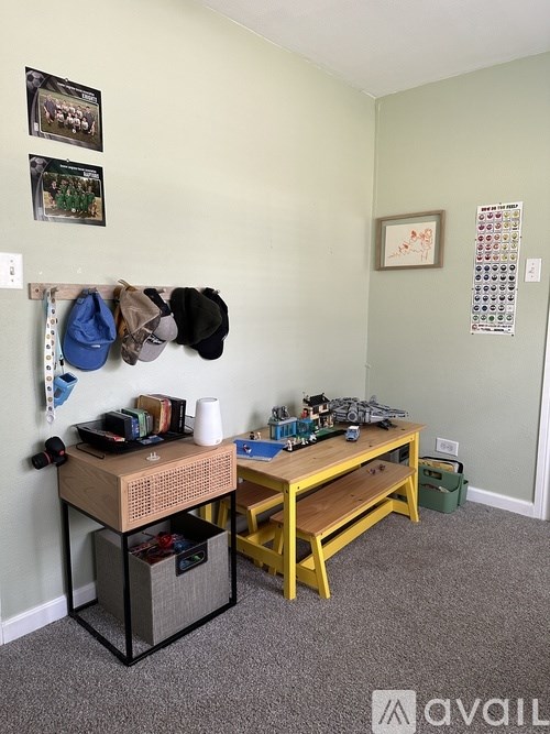 A room with a desk, chair, and coat rack.