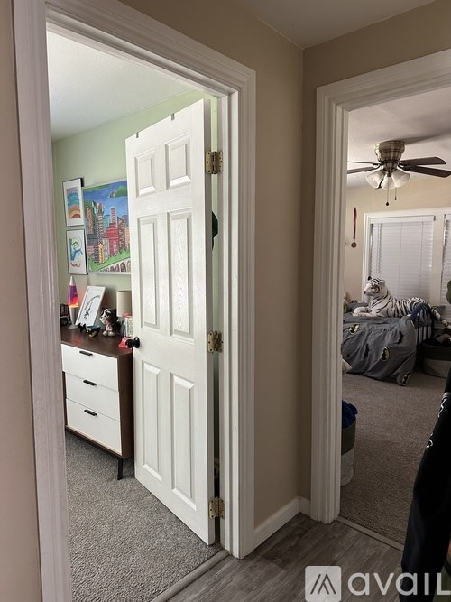 A white door is open to a room with a ceiling fan and a bed.
