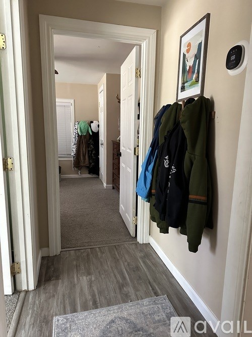 A hallway with a coat rack and a doorway.