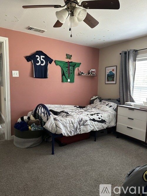 A bedroom with a bed, dresser, and two jerseys hanging on the wall.
