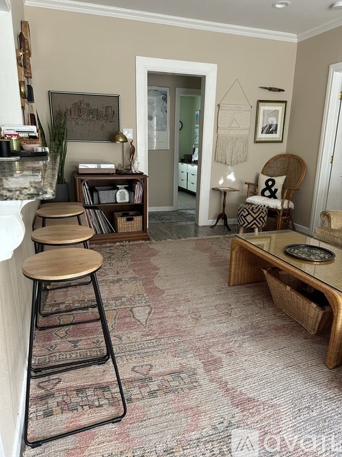A living room with a rug on the floor and a chair in the corner.