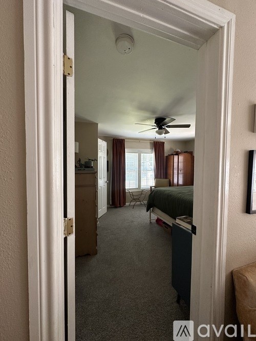 A room with a bed, a chair, and a ceiling fan.