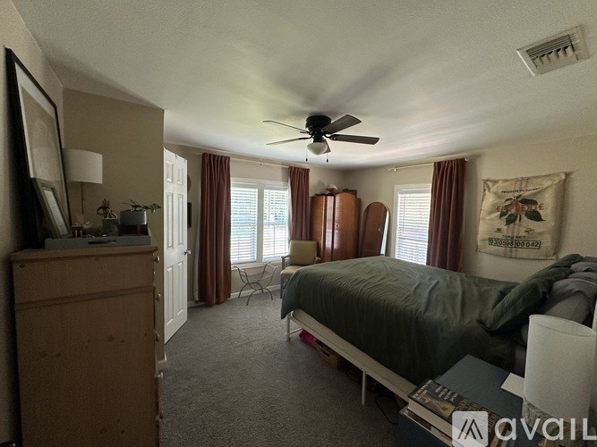 A bedroom with a bed, dresser, and window with curtains.