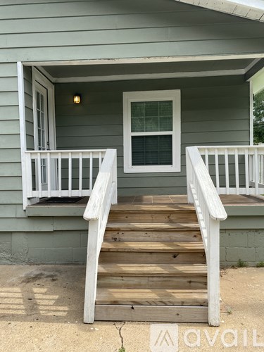 A house with a green siding and a white porch.