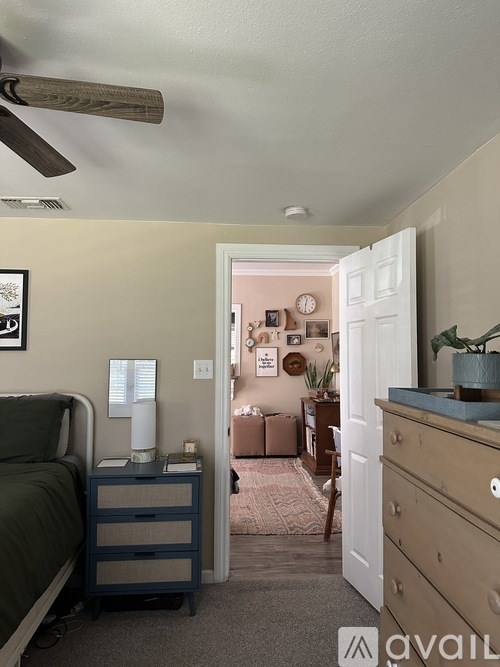 A room with a bed, a dresser, and a ceiling fan.