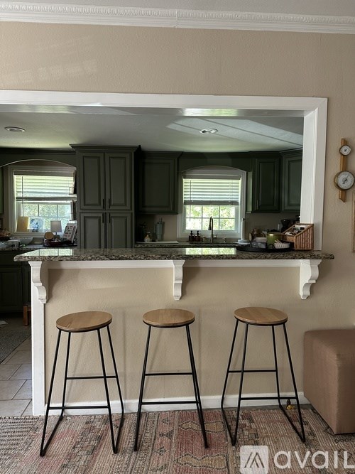 A kitchen with a bar area featuring two stools.