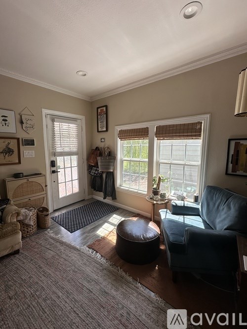 A living room with a brown ottoman, a blue chair, and a rug.