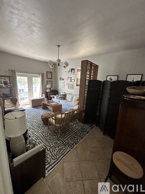 A living room with a patterned rug and a wooden stool.