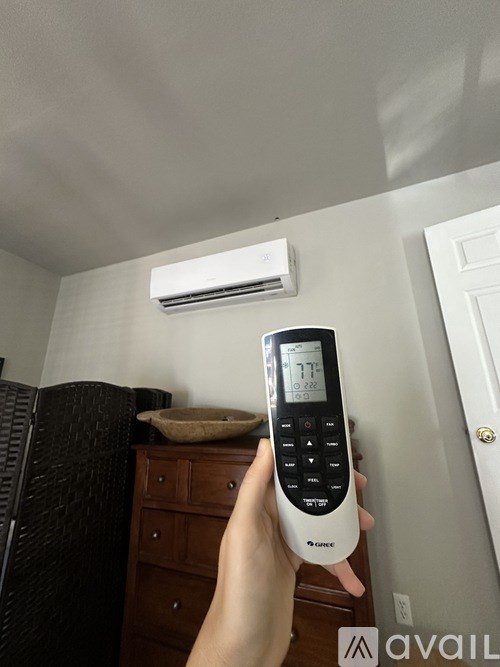 A person is holding a remote control with a digital display showing the temperature.