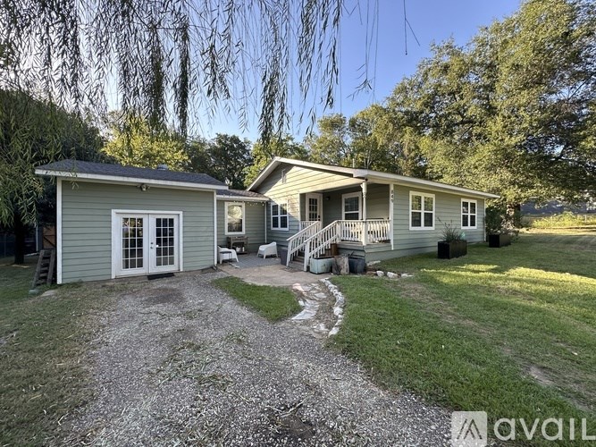 A house with a gravel driveway and a tree in the background.