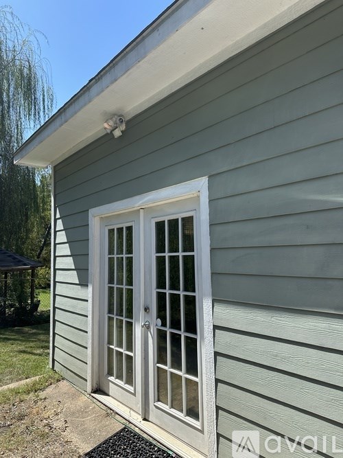 A house with a grey siding and a white door with glass panels.
