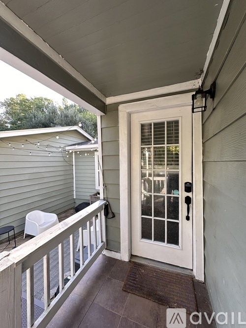 A white door with a glass window is on the right side of a porch.