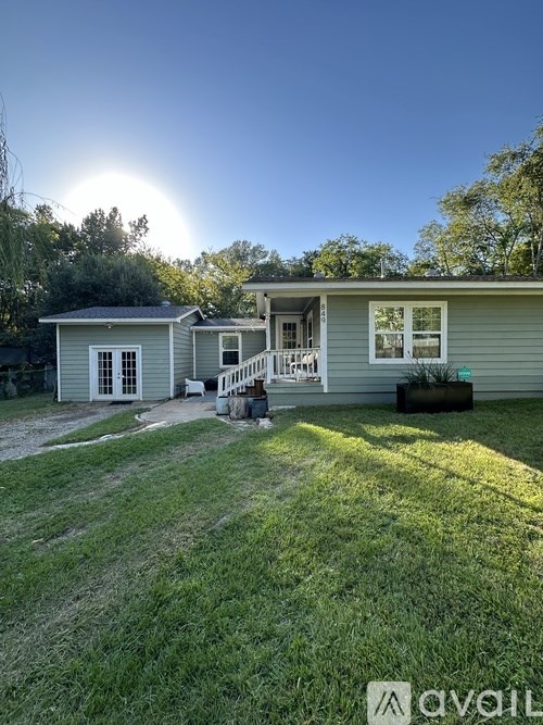 A house with a green lawn and a sunny sky in the background.