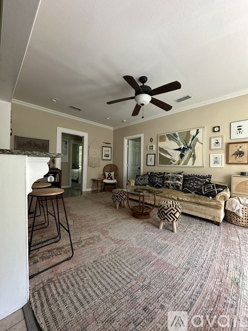 A living room with a couch, a rug, and a ceiling fan.