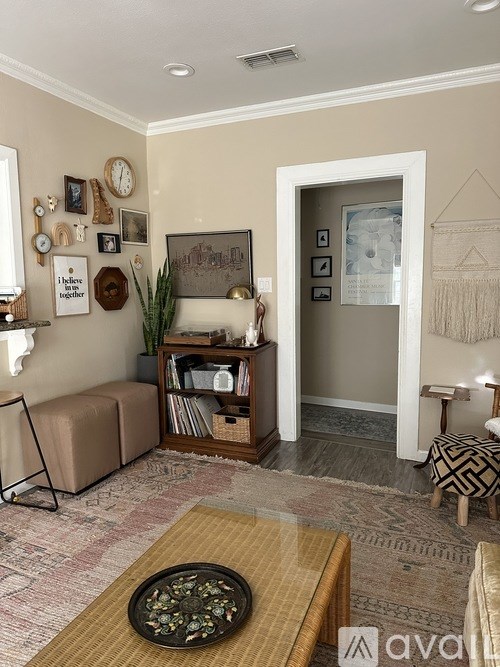 A living room with a sofa, a coffee table, and a wall with various pictures and clocks.
