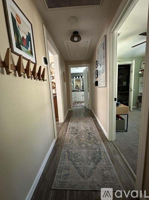 A hallway with a rug on the floor and a few pictures on the wall.