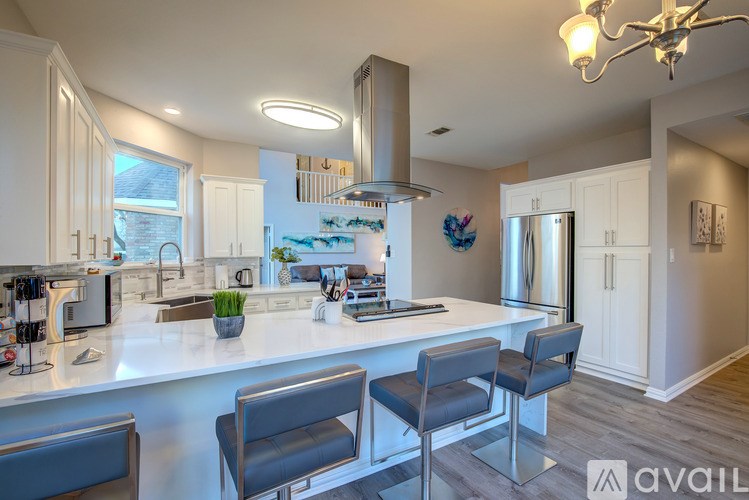 A kitchen with a white countertop and grey chairs.