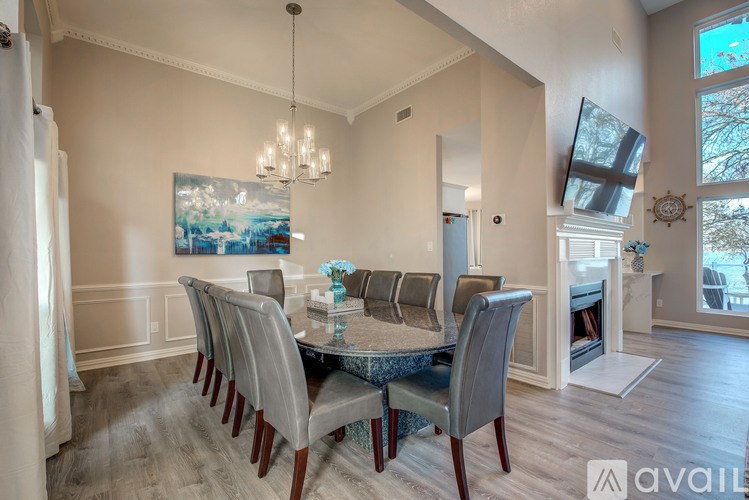 A dining room with a table set for six and a painting on the wall.