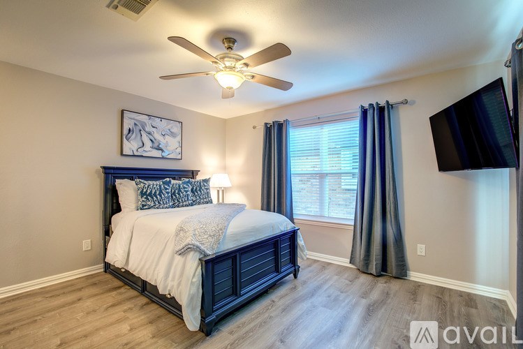 A bedroom with a bed, a ceiling fan, and a window with curtains.