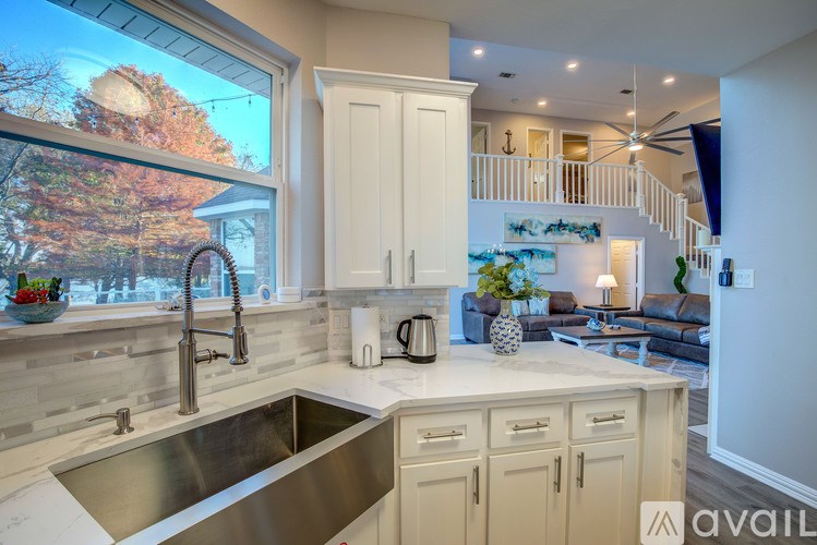 A kitchen with a stainless steel sink and white cabinets.