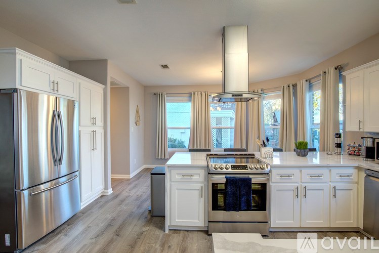 A kitchen with white cabinets and a stainless steel refrigerator.