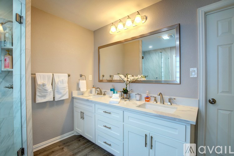 A bathroom with a marble countertop and white cabinets.