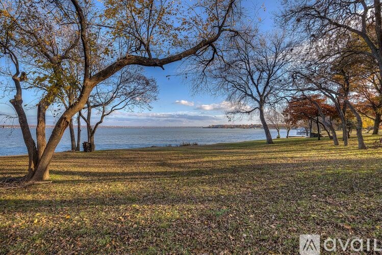 A serene landscape with trees, grass, and a body of water.