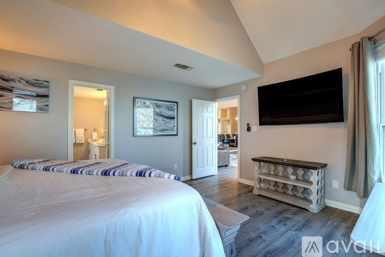 A bedroom with a large bed and a flat screen TV mounted on the wall.