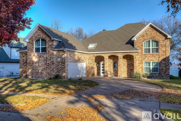 A house with a stone facade and a driveway in front.