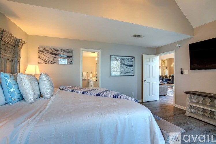 A bedroom with a large bed and a painting on the wall.