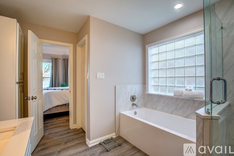 A bathroom with a tub, sink, and a window with blinds.