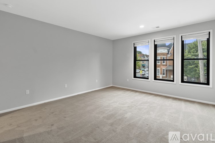 A spacious room with a carpeted floor and a large window showing a view of a building and trees.