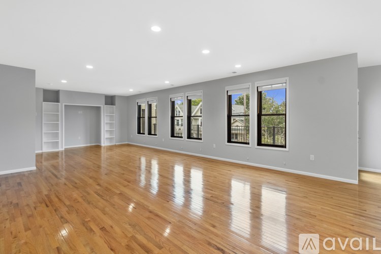 A spacious room with wooden floors and large windows.