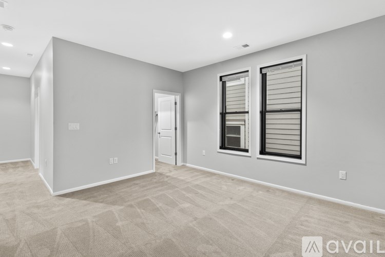 A spacious room with a carpeted floor and a window with blinds.