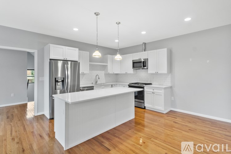 A modern kitchen with white cabinets and a wooden floor.