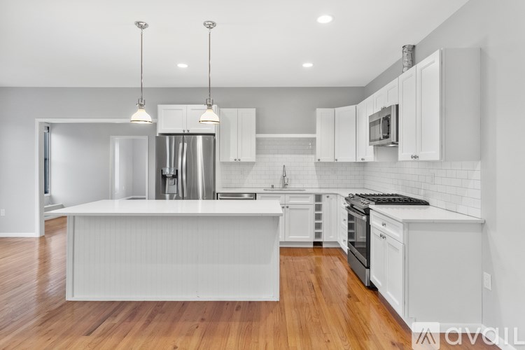 A modern kitchen with white cabinets and a wooden floor.