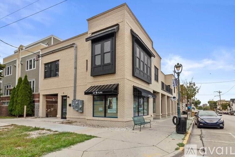 A street view of a building with a black awning and a car parked in front.