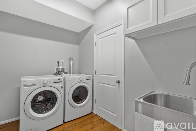 A laundry room with a washer and dryer, a sink, and a cabinet.