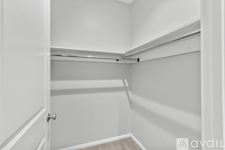 A white closet with a door and a shelf.