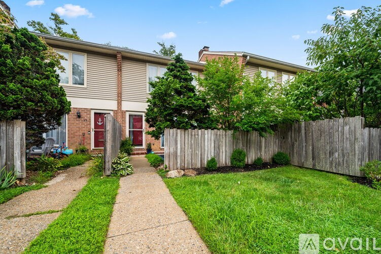 A house with a red door is surrounded by a wooden fence and greenery.